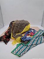 Group of four scarves with various patterns and colors, including silk and mixed materials