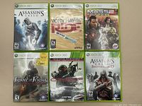 Photo showing 6 Xbox 360 game cases: Assassin's Creed, Tony Hawk Ride, Mass Effect 2, Prince of Persia, Crysis Warhead, Assassin's Creed Brotherhood.