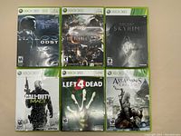 Lot of 6 Xbox 360 game cases laid out showing cover art for Halo 3 ODST, Lost Planet 2, Skyrim, Call of Duty MW3, Left 4 Dead, Assassin's Creed III