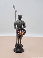 Full view of the standing medieval knight figurine on black pedestal, holding spear and shield