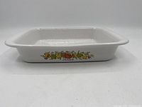 Side angle photo showing overall shape and vegetable pattern on side of the vintage Corningware casserole dish.