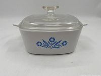 Front view of rectangular Corningware dish with blue cornflower pattern and glass lid on top.
