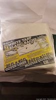 Packed brand new Polytuf 7 mil white tarp showing product label with size and features.