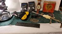 Mixed lot featuring socks, watch, tobacco tin, plaque, figurines, butterfly knife, and metal rod with wrapped handle on a table