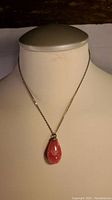 Necklace displayed on mannequin showing the pink teardrop gemstone pendant and metal chain.