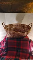 Front angled view of the woven basket showing the open weave pattern and one handle.