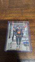 Image of Connor McDavid hockey trading card in protective plastic case on wooden surface.