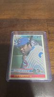 Photo of a Joe Carter baseball card from 1984 Donruss series showing Rated Rookie status with Chicago Cubs uniform.