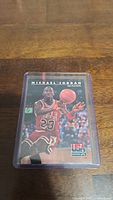 Clear photo of Michael Jordan NBA Playoffs basketball trading card in protective sleeve on wooden surface.