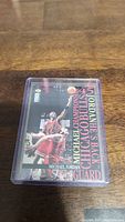 Photo of a Michael Jordan Chicago Bulls basketball card in a protective plastic case showing action shot and player details.