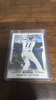 Photo of Shohei Ohtani rookie baseball card in protective plastic sleeve, showing him batting in white uniform with number 11.