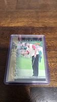 Photo of Tiger Woods rookie baseball card in protective sleeve on wooden surface.