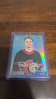 Front of Tim Stutzle rookie hockey card with holographic background, featuring player in black Ottawa Senators jersey.