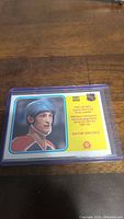 Front view of 1981-82 Wayne Gretzky O-Pee-Chee rookie hockey card inside a protective card sleeve, on a wooden surface.