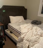 Full view of queen bed with headboard, mattress on frame and trundle below.