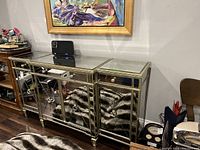Full view of mirrored sideboard cabinet with reflective glass panels and drawers on top, some objects on top of it.