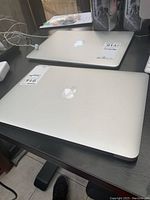 Two MacBook Air laptops closed on desk; front unit labeled 914