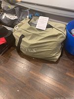 Intex kayak packed in a beige carry bag on hardwood floor, showing the brand logo.