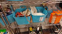Photo of blue plastic baskets with various cords and small items inside, plus orange plastic organizer on a metal rack shelf.