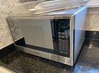 Panasonic microwave oven with stainless steel finish on a granite countertop, digital clock showing 12:31, and keypad visible.