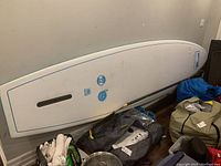 Board leaning against wall with paddle and bag