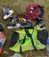 Bauer and Nike skates with bags and snorkeling flippers outdoors on grass