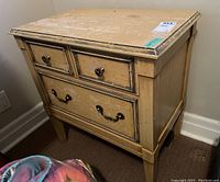 Full side view of the distressed wood side table showing two drawers with metal pulls and finish flaws.