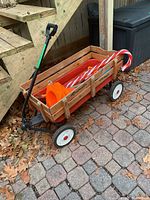 Wooden Roadmaster woody wagon on paved ground under stairs with orange traffic pylons, toy shovels, and candy cane decorations inside.
