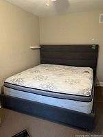 Full view of king size bed frame with headboard and mattress in room corner