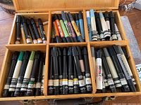 Wooden marker box with multiple marker pens including OLO chalk markers and assorted graphic markers.