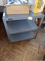 Full view of the gray Durham metal media cart showing two shelves and some items placed on top