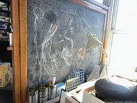 Close-up view of the chalkboard surface with chalk drawings and wood frame showing container tray at bottom.