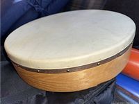 Top view of the Cooperman frame drum showing the natural skin head with wear and metal band rim, placed on a blue padded carry case.