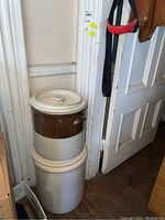 Both farmhouse crocks stacked in corner near doorway, showing relative size and condition.