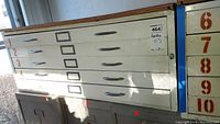 Side front view of metal flat file cabinet showing drawers numbered 1 to 10 and plywood top.