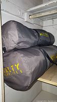 Two grey Kelty Domolite 6 tent bags stacked on a shelf.