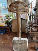 Overall view of wicker floor lamp beside white box fan in room