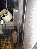 Two floor lamps with wooden bodies and frosted glass cylinders, one tall and one shorter, shown next to a window and radiator.