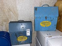Front view of two metal Leaktite Brush Keeper paint brush boxes, showing paint stains and labels