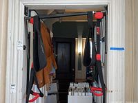 Full view of complete pull up bar mounted in doorway with hanging straps and handles.