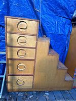 Photo of the front left side showing four drawers with oval handles and the stair steps to the right.