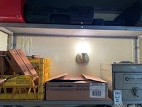 Wide shot of shelving with various tools and storage boxes including wooden clamps and a yellow crate