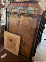 Multiple framed Tibetan art prints stacked leaning against a piece of furniture, showing some prints with skull motifs and traditional Tibetan imagery.