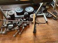 Overview of cast iron plates, bars, hex dumbbells and push-up handles on hardwood floor
