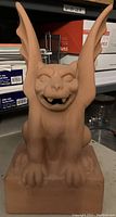 Front view of the terracotta gargoyle statue showing its facial features and wings.