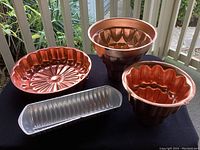 Four vintage aspic and jello molds: one silver tone aluminum loaf-shaped mold and three pink copper molds (two Turks head and one scalloped). All molds are in excellent condition with built-in wall-mounted hooks.