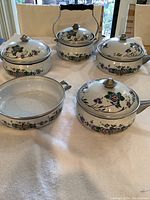 Front view of the 9 piece set showing the tea kettle, three pots, and a sauté pot with floral enamelware design.
