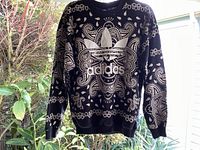 Front view of black Adidas pullover sweatshirt with white parsley bandana print and large white foil Adidas trefoil logo centered on chest.