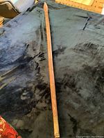 Full view of wooden spear showing length and carved details along shaft