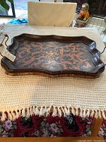 Top-down view of the vintage wood bed tray with decorative floral pattern and raised side handles.
